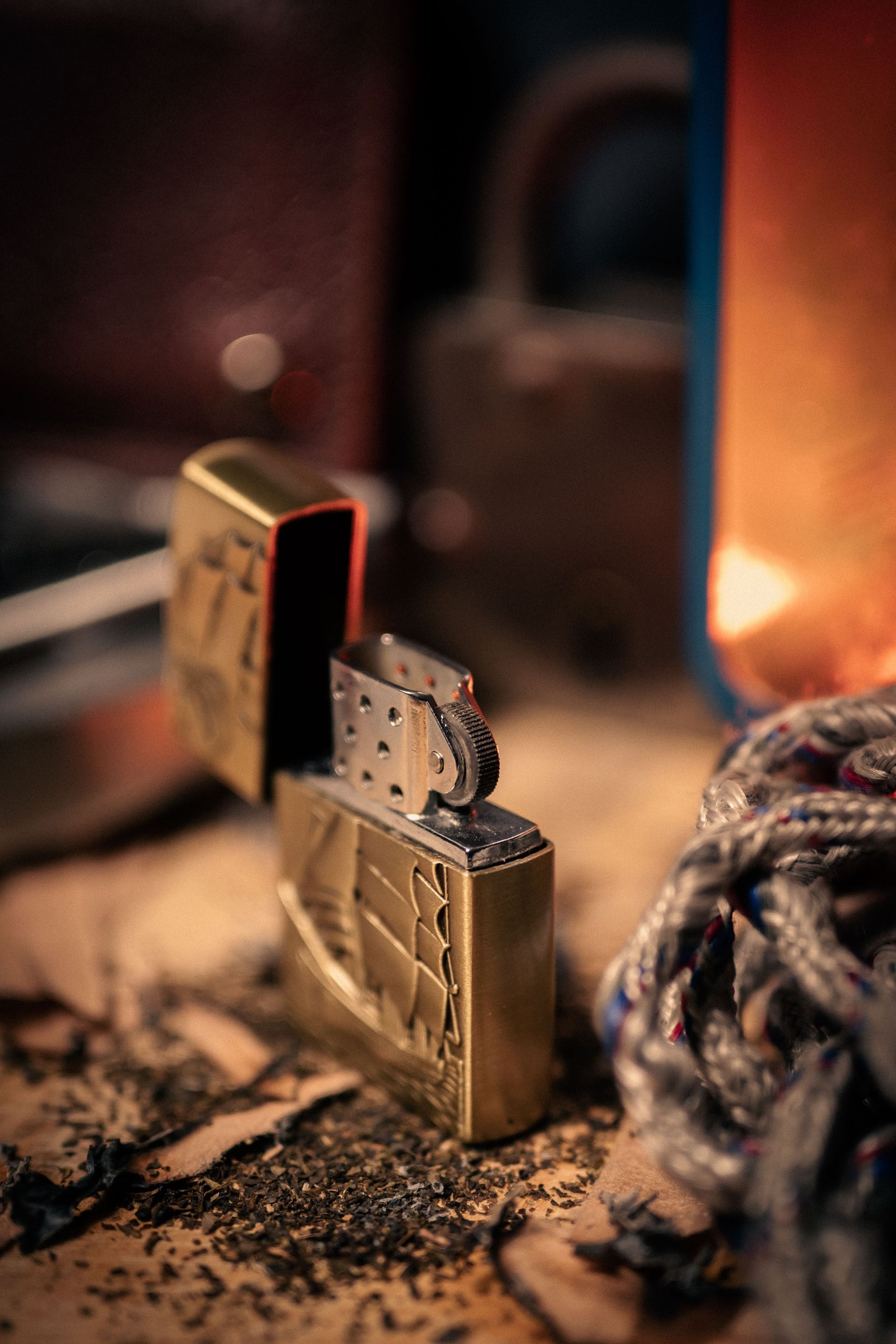 Artistic close-up of a vintage brass lighter on a rustic table with dramatic lighting.